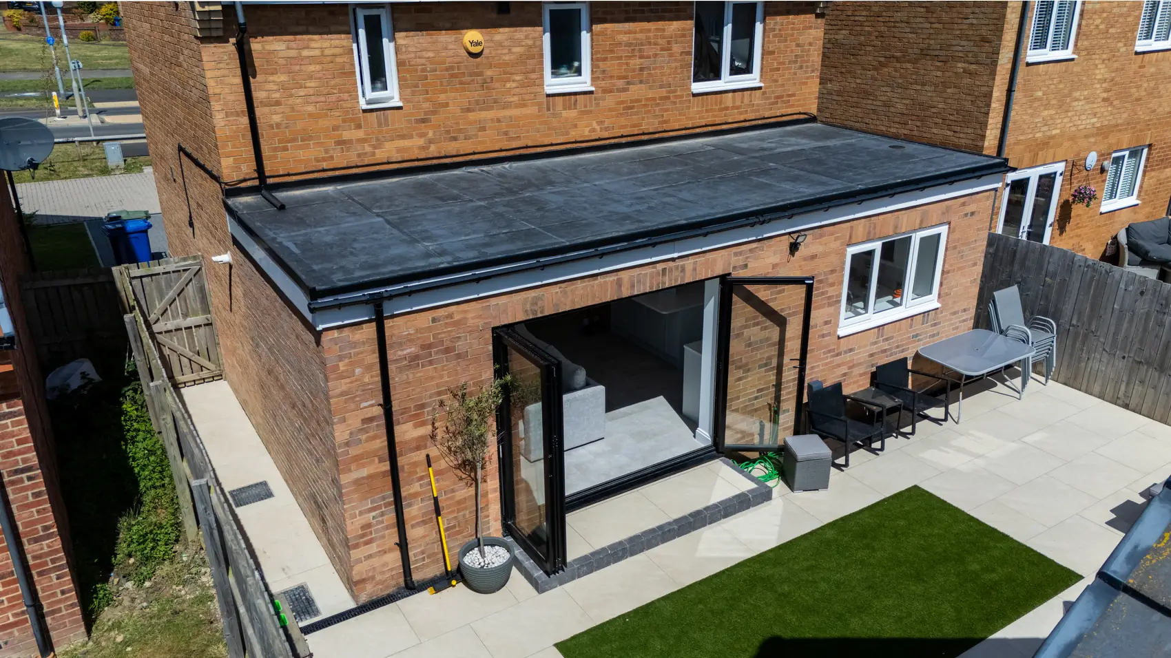 Completed single-storey rear extension with dark aluminium sliding doors and new patio, aerial view